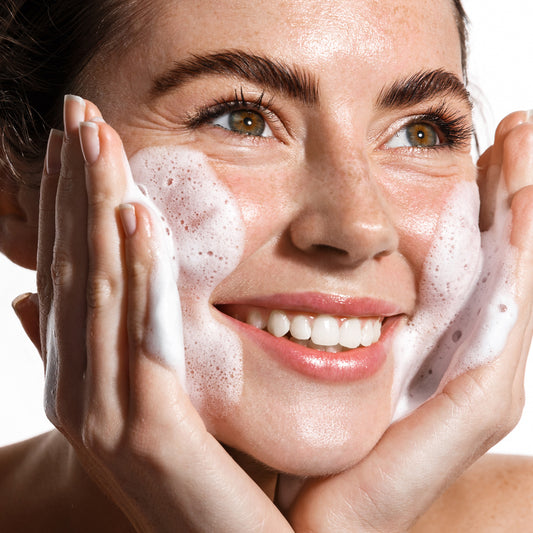 Person applying BioAcne Micellar Foam on their face, showcasing its gentle cleansing properties.